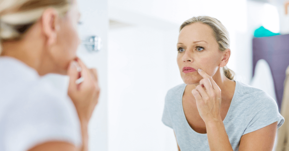 Woman looking into a mirror before anti-wrinkle injections at Derma Medica